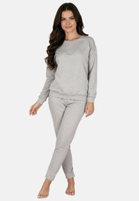 Szürke melegítőnadrág és hozzá illő hosszú ujjú felső puha anyagból, kerek nyakkivágással, bordázott mandzsettákkal és szűkített szárakkal.