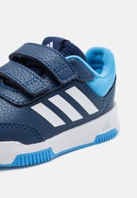 Scarpe da ginnastica blu navy con un upper testurizzato, dotate di strisce bianche, chiusure a strappo e un interno e una suola di colore blu chiaro.