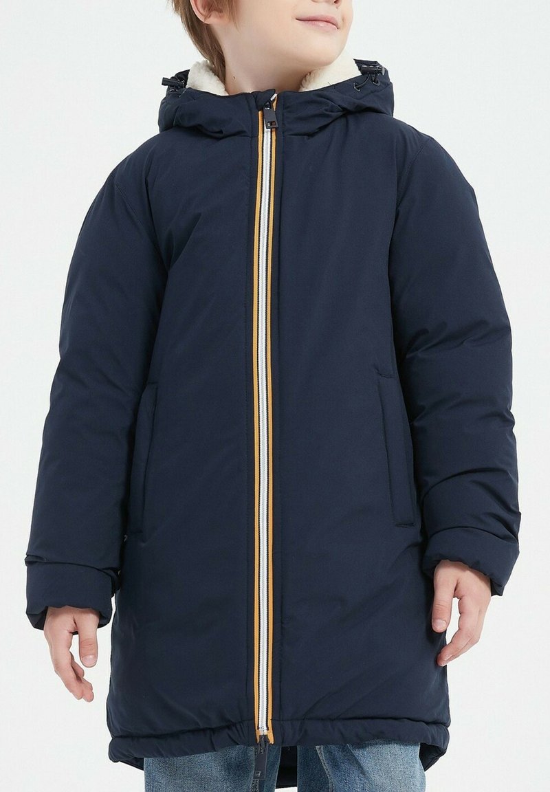 Manteau matelassé navy avec une capuche en polaire blanche, doté d'une fermeture éclair avant avec des accents jaunes et blancs et de poches latérales.