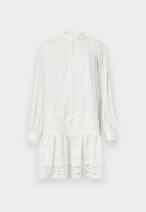 Robe blanche avec des manches longues et un col haut. Présente des motifs en dentelle complexes, un tissu texturé et un ourlet superposé. Fermeture à boutons à l'avant.