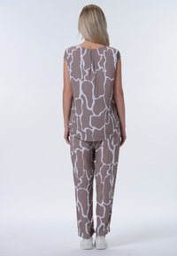 Set coordinato di top e pantaloni a righe marroni e bianche con vestibilità ampia e maniche corte, realizzato in un tessuto leggero. Indossate scarpe bianche.