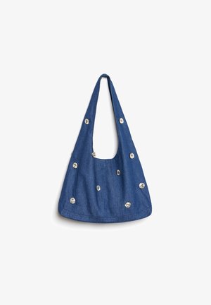 Denim schoudertas met een gebogen vorm, voorzien van zilverkleurige versieringen die gelijkmatig over het oppervlak zijn verdeeld en een enkele brede schouderband.
