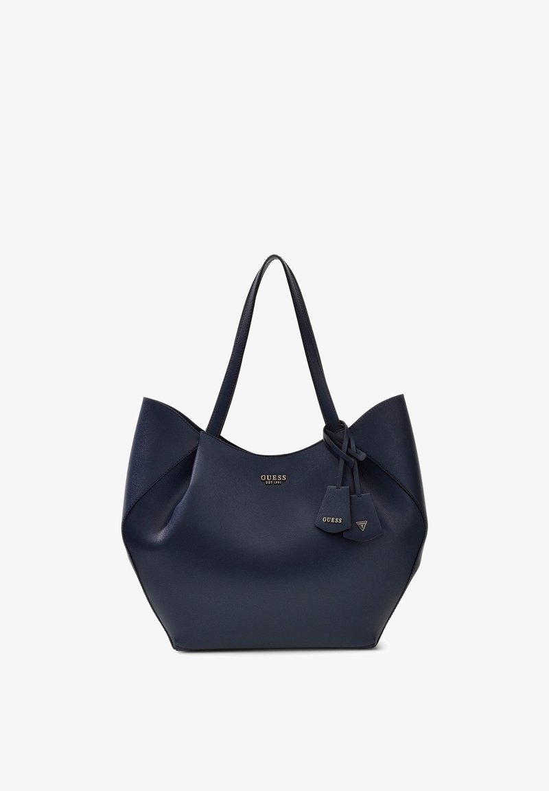 Sac cabas bleu marine Guess avec deux bretelles et petites étiquettes suspendues, avec logo Guess doré au centre avant.