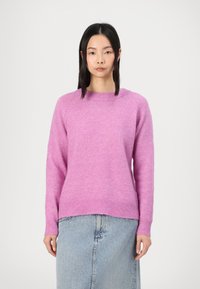 Roza pletena hoodie s okruglim izrezom, rebrastim manžetama i donjim rubom, meke teksture, u kombinaciji s traper suknjom. Jednostavan i minimalistički dizajn.