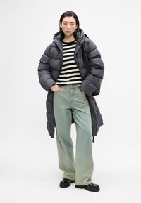 Abrigo largo gris esponjoso, camiseta de rayas blancas y negras, jeans de pierna ancha azul claro, botas negras gruesas, estilo minimalista, textura suave.