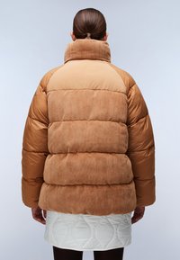 Kurtka puchowa z wysokim kołnierzem, wykonana z brązowego sztruksu i pikowanej tkaniny, charakteryzująca się objętościowym kształtem oraz żebrowaną teksturą w dolnej części.
