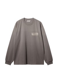 Szara koszulka z długim rękawem typu crewneck z ściągaczami, małe białe logo "Carhartt WIP" na lewej piersi oraz metka rozmiaru wewnątrz kołnierza.