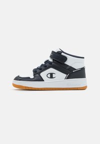 High-top sneakers featuring a white and navy leather upper, padded collar, adjustable strap, and a gum rubber sole.