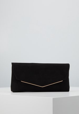 Musta suorakaiteen muotoinen clutch-laukku, jossa on kärjellinen läppä ja ohut kullanvärinen koriste valkoisella pinnalla vaaleanharmaata taustaa vasten.