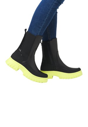 Schwarze Knöchelstiefel mit einer klobigen gelben Sohle; glattes Material, seitlicher Reißverschluss und elastische Einsätze für ein einfaches Anziehen.