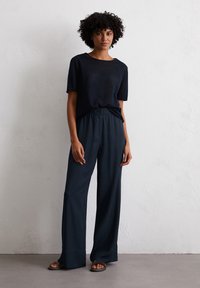 Marineblauwe lichtgewicht T-shirt met korte mouwen, gecombineerd met marineblauwe broek met wijde pijpen, voorzien van een ontspannen pasvorm en elastische tailleband.