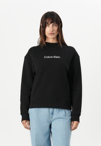 Zwarte sweatshirt van een katoenmix met ribgebreide manchetten en hem, met het witte "Calvin Klein" logo gecentreerd op de borst.