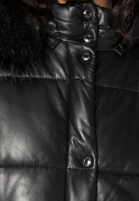 Černá kožená péřová bunda s prošívaným designem, vysokým límcem, velkým černým kožešinovým lemováním a lesklými knoflíky na zapínání.