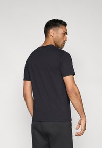 Must puuvillast lühikeste varrukatega t-särk, millel on ümar kaelus. Tagaküljel on sile tekstuur ja lihtne disain ilma mustrite või rõhutusteta.