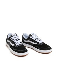 Black suede sneakers with white laces and accents, featuring a distinctive wave design, rubber sole, and padded collar for comfort.