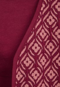 Bordeaux stoffen paneel met een textuur van roze bloemen en zigzagpatronen, met een glad oppervlak en contrasterende rand.