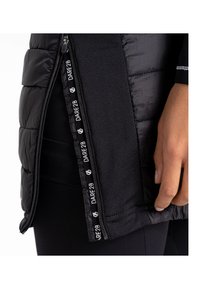 Schwarze Pufferjacke mit gestepptem Design, Reißverschluss mit Stoff-Ziehlasche und Logodetails entlang der Innenkante.