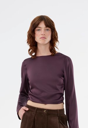 Lilla satin langærmet top med firkantet udskæring og en cropped silhuet. Glat tekstur med en afslappet pasform, parret med brune kordfløjspants.