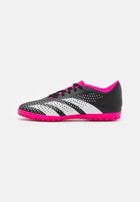 Scarpe da ginnastica bianco e nere con una parte superiore strutturata, dettagli rosa e una suola in gomma caratterizzata da piccole punte per aderenza.