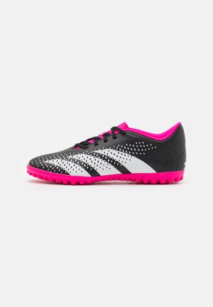Scarpe da ginnastica bianco e nere con una parte superiore strutturata, dettagli rosa e una suola in gomma caratterizzata da piccole punte per aderenza.