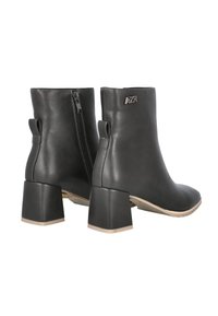 Botines de cuero negro con tacón de bloque, con una cremallera en la parte trasera y un detalle con el logo en el lateral. Textura lisa, diseño aerodinámico.