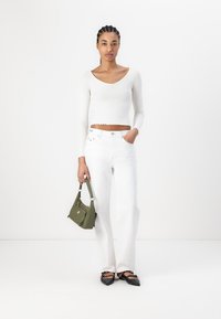Hvit kortermet langermet topp med bølget kant, hvite høytlivsjeans, svarte spisse leiligheter, og en olivengrønn håndveske.