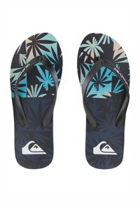 Une paire de tongs noires et bleues avec des motifs de feuilles tropicales et des sangles en caoutchouc noires, arborant un logo de vague blanche près des orteils.