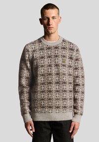 Πλεκτό πουλόβερ σε ανοιχτό γκρι με καφέ γεωμετρικό μοτίβο. Διαθέτει ριμπ μανσέτες και κάτω μέρος, με ένα μικρό κίτρινο λογότυπο στο στήθος.