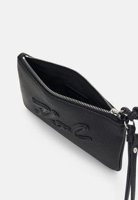 Svart strukturerad läderkuvert med dragkedjestängning. Har en upphöjd logotypdesign och en avtagbar rem för mångsidighet. Inuti är den klädd med tyg.