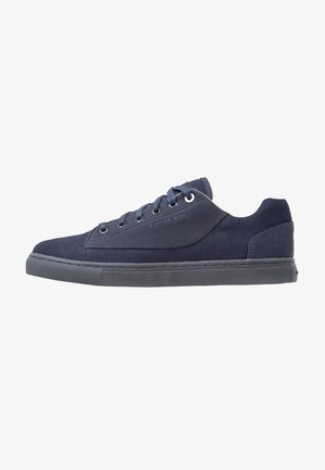 Männliche navyblaue Low-Top-Sneaker mit Schnürverschluss und grauer Gummisohle, seitlich geprägt mit Markenname.