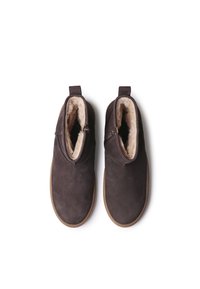 Bottines en suède marron avec une doublure en fourrure douce, bout arrondi et fermeture éclair sur le côté ; elles disposent d'une languette à l'arrière et d'une semelle en caoutchouc.