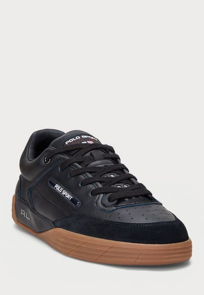 Black leather and suede sneaker with round toe, textured upper, dark blue accents, perforated detailing, and a gum rubber outsole.