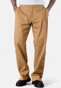 Beige, straight-leg pants made of durable fabric featuring side pockets and a button closure. Smooth texture with a classic design.