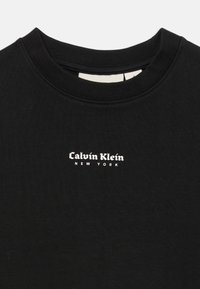 Černý mikina s kulatým výstřihem vyrobená z bavlny, s ribovaným límcem a bílým nápisem „Calvin Klein NEW YORK“ na přední straně. Hladký povrch.