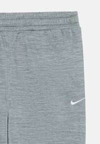 Sive športne hlače z meliranim vzorcem, elastičnim pasom in belim logotipom Nike na spodnji levi strani.