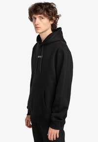 Sudadera con capucha negra, confeccionada en una mezcla de algodón. Presenta un bolsillo frontal, puños acanalados y un pequeño logotipo bordado en el pecho.