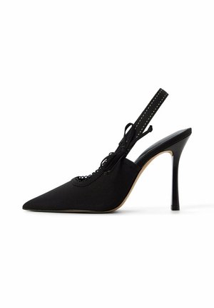 Zwarte slingback pumps met spitse neus, hoge hak, enkelriempje en decoratieve strik op witte achtergrond.