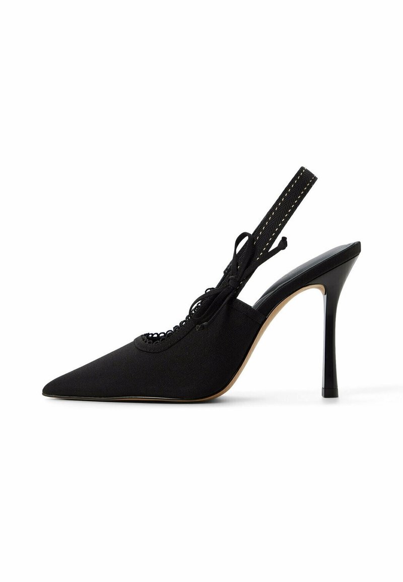 Chaussure à talon haut noire à bout pointu, dos sling avec bride à la cheville et nœud décoratif sur fond blanc.