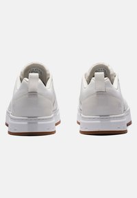 Sneaker bianche con tomaia liscia, forma arrotondata e linguette di estrazione. La suola è bianca con una suola in gomma marrone. Logo del marchio sul tallone.