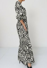 Robe maxi en imprimé zèbre noir et blanc, fabriquée dans un tissu léger. Dotée de manches bouffantes, d'une taille cintrée et d'un ourlet froncé.
