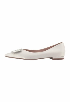 Ballerines blanches pointues avec un petit talon et une embellissement décoratif en argent sur le bout. Texture lisse et design minimaliste.