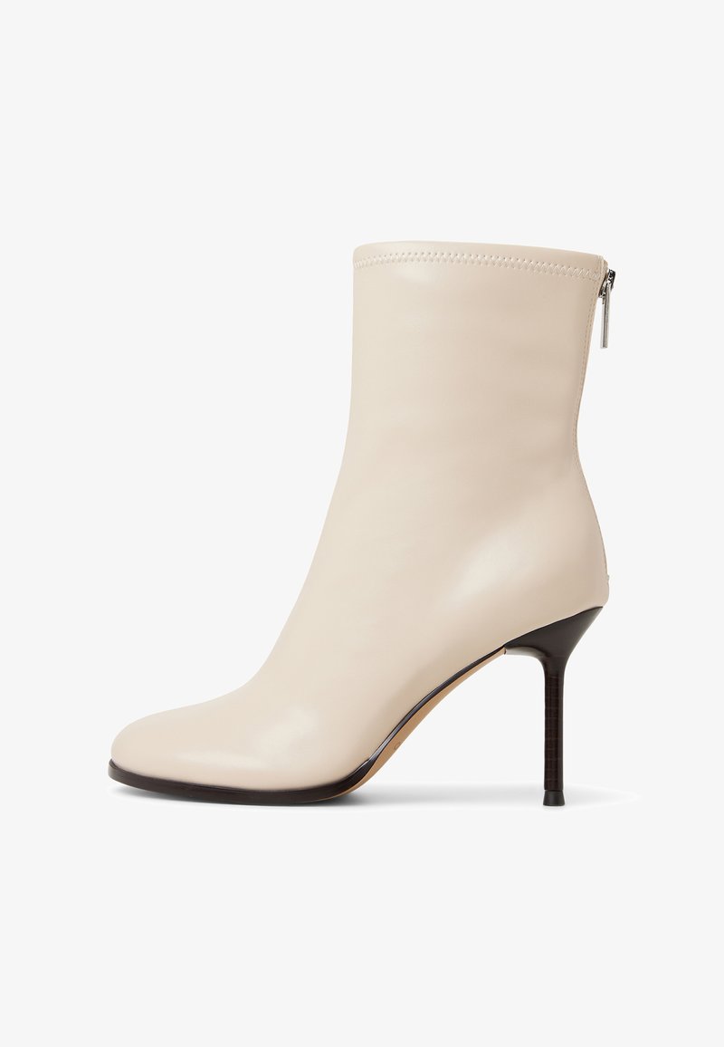 Bottine en cuir beige avec une silhouette élancée, un bout pointu et un talon aiguille fin. Dotée d'une fermeture éclair sur le côté pour un enfilage facile.