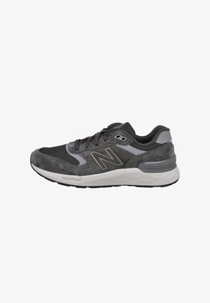 Zapatilla deportiva gris que presenta una combinación de materiales de malla y ante, con una entresuela de espuma, acentos estampados y detalles reflectantes.
