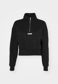Felpa nera cropped Levi's con maniche lunghe, colletto alto, zip frontale e tasca a marsupio su sfondo grigio chiaro.
