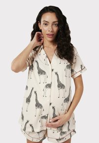 Conjunto de pijama de manga corta en tejido crema, con un patrón de jirafas, que incluye una parte superior con botón y pantalones cortos a juego, adornados con ribete rojo.