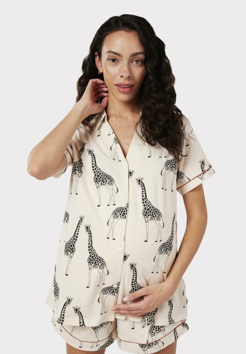 Conjunto de pijama de manga corta en tejido crema, con un patrón de jirafas, que incluye una parte superior con botón y pantalones cortos a juego, adornados con ribete rojo.