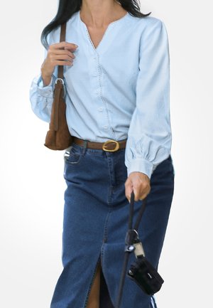 Světle modrá proužkovaná halenka s výstřihem do V a předními knoflíky, kombinovaná s džínovou sukní s bočním rozparkem, doplněná hnědým páskem a kabelkou.
