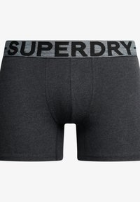 Zwarte katoenen boxershorts met een grijze elastische tailleband. De tailleband heeft "SUPERDRY" in vette zwarte letters. Glad oppervlak.