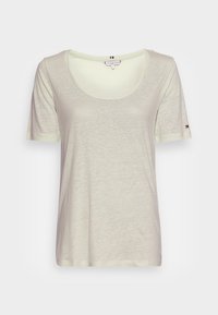 T-shirt corto a maniche corte color beige chiaro con scollatura a girocollo, tessuto morbido e un piccolo logo accento sulla manica. Vestibilità leggermente ampia.