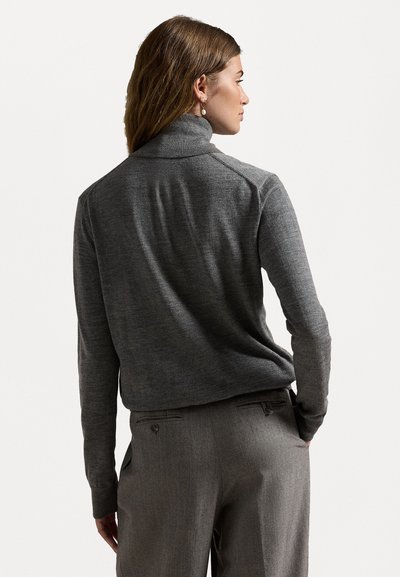 Grå genser med høy krage, laget av fint strikket stoff. Den har lange ermer og en løs passform, kombinert med grå bukser i en lignende nyanse.